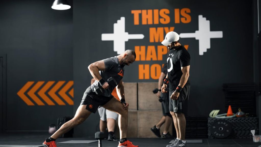 Two men working out with dumbbells in a Bahrain gym, demonstrating strength and fitness.