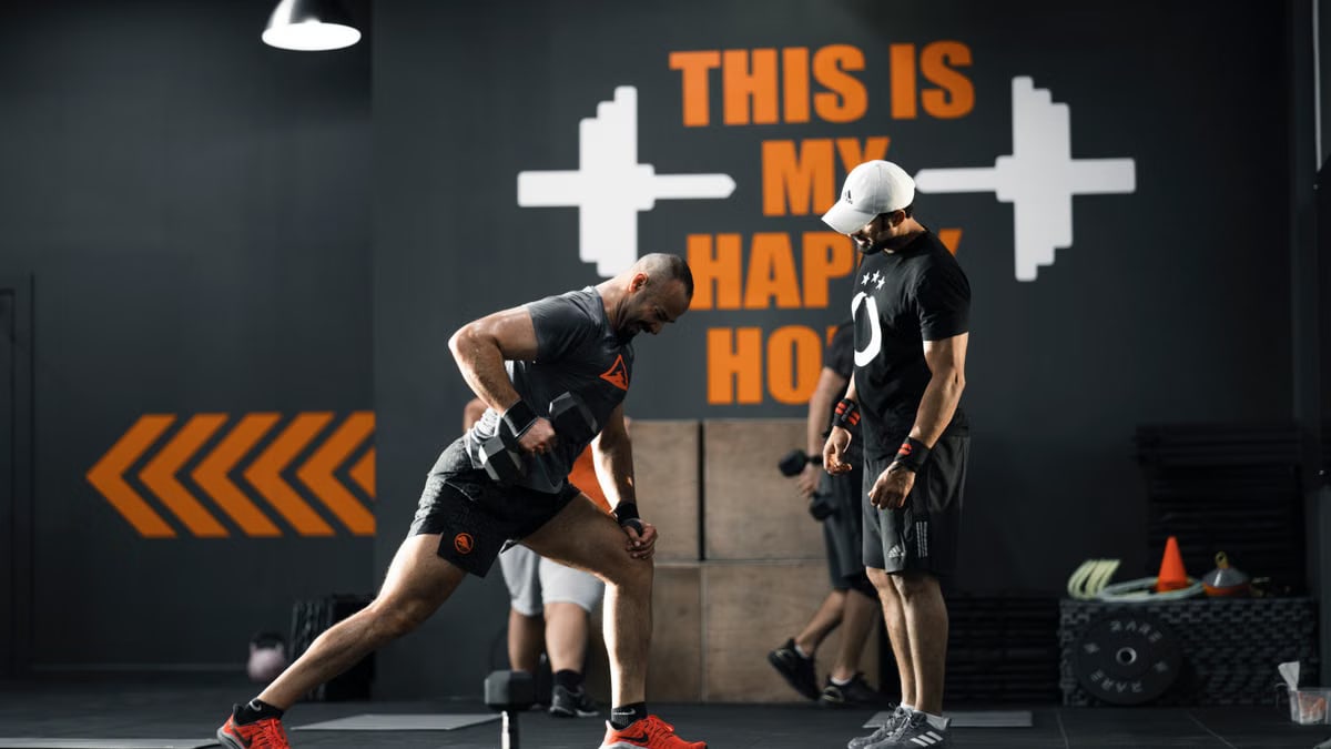 Two men working out with dumbbells in a Bahrain gym, demonstrating strength and fitness.